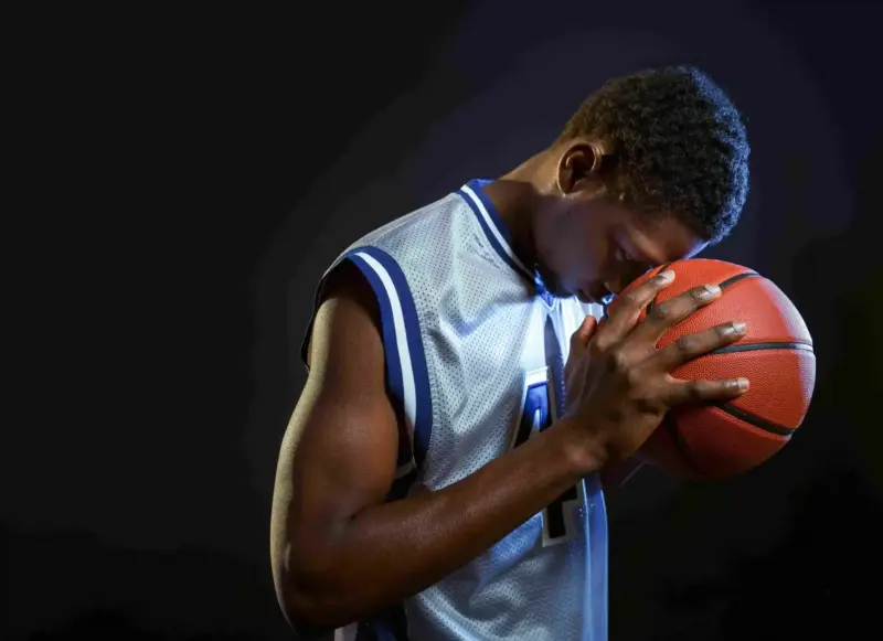 Athlete holding a basketball with eyes closed in deep mental focus