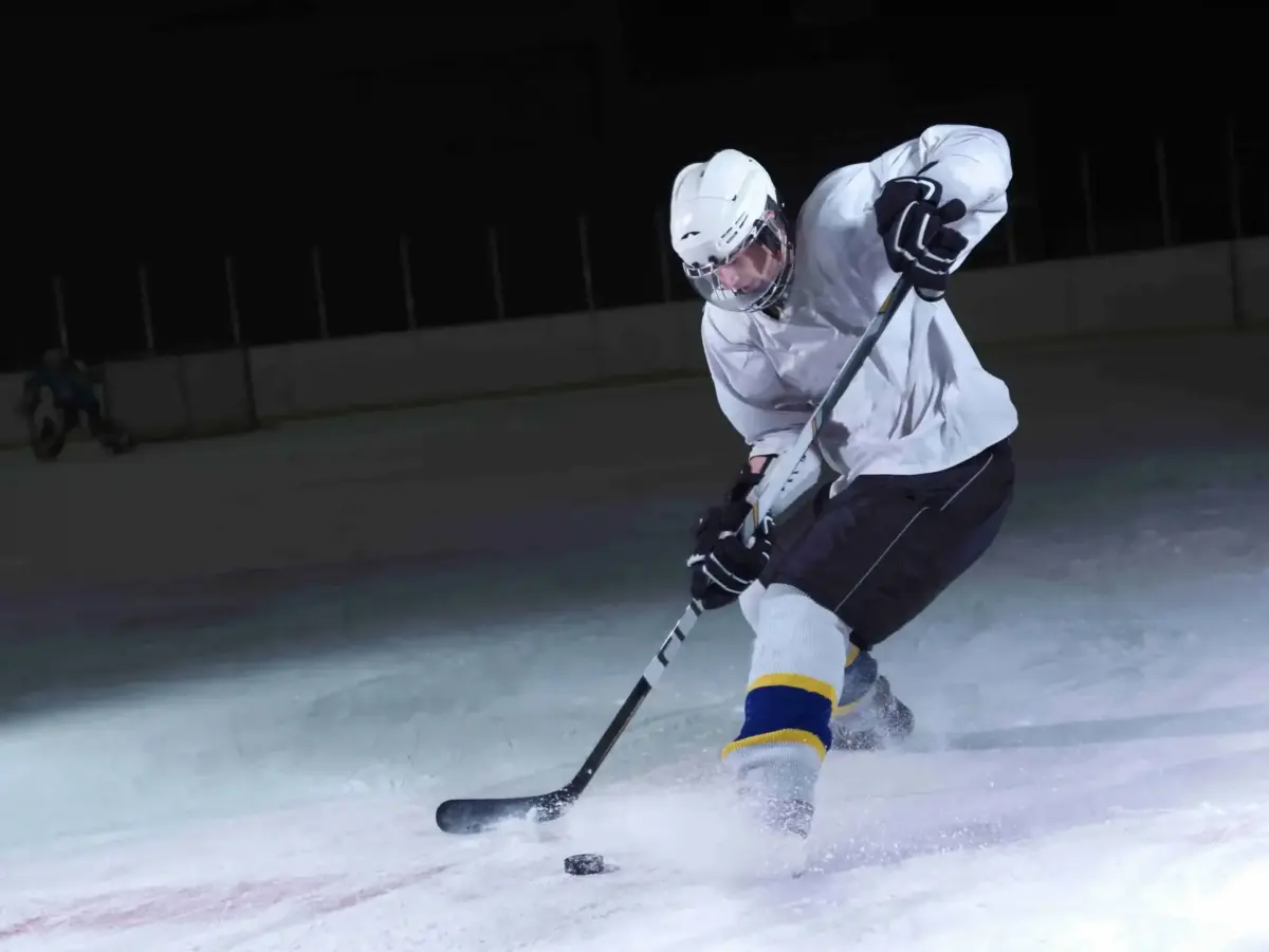 Hockey player making a powerful turn on a dark ice rink