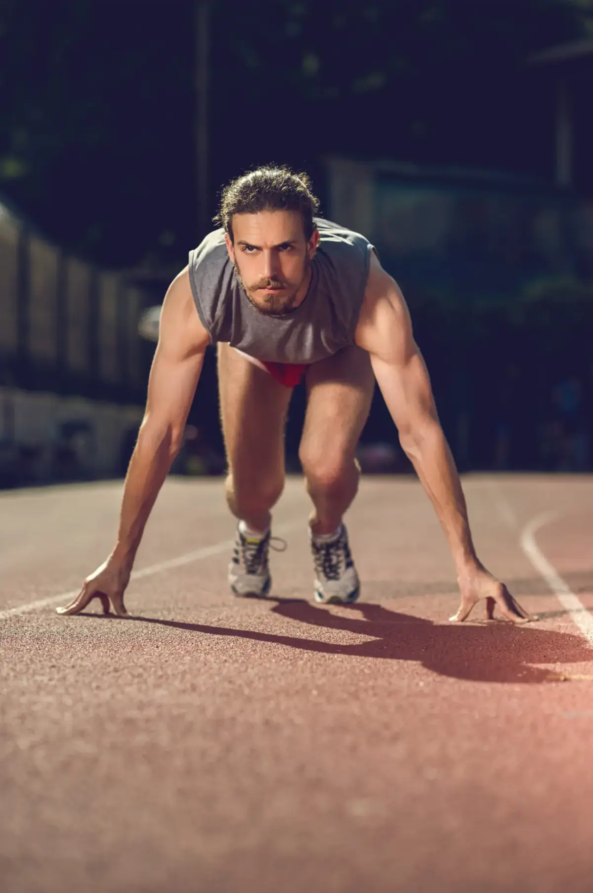 Sprinter in the starting position on a track at night