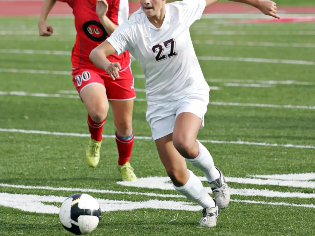 Two youth soccer players racing for the ball during a match